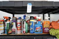 Front view of various bottles and cans including cleaning and pest control products arranged on a shelf