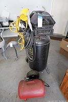 Full view of black Craftsman air compressor with yellow hoses and red portable air tank at its base