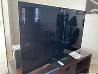 Front view of LG OLED television on wooden shelf with screen off