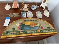 Wide angle showing all items on the tabletop, including the wooden wall hanging and various angel ornaments.