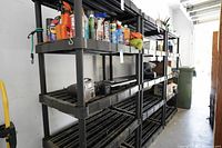Side view of black plastic shelving units with various items on shelves (not included).