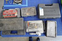 Overview of six tool cases including sets from Craftsman and Workman's Choice, arranged on blue surface