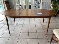 Front view of oval teak dining table with one leaf removed