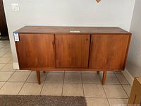 Front view showing three sliding doors and tapered legs