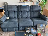 Front view of three-seat blue fabric reclining sofa with books displayed in front