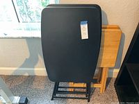 Set of 4 black TV trays stacked with foldable metal legs visible, showing black molded rectangular surfaces with rounded corners.