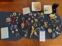 Overall assortment of jewelry items on table including cases, brooches, earrings, pendants, cufflinks, charms, and rings