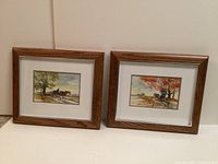 Pair of framed watercolour paintings showing Mennonite horse-drawn buggies in rural settings, displayed side-by-side against a neutral background.