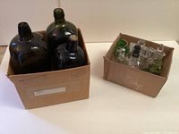 Three large antique green bottles in a cardboard box