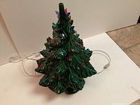 Photo of vintage green ceramic Christmas tree with colorful light bulbs and electric cord.