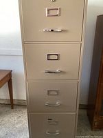 Front view of the beige 4 drawer filing cabinet showing drawer handles and label holders.