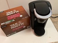 Photo showing black Keurig coffee machine next to a full box of Van Houtte coffee pods with 80 original house blend pods