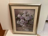 Photo of large framed flower painting featuring white and light purple flowers in a silver vase against a soft background.