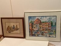 Two framed watercolor paintings by Dr. J Cooper: left shows four seated figures, right shows street scene with domed building.