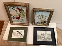 Four framed artworks including two cardinal paintings, a yellow bird painting, and a cityscape sketch.