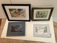 Photo shows four framed and matted art pieces arranged on white background, including floral and winter theme paintings.