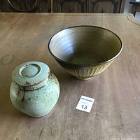 Photo showing both pottery pieces: a large earth toned ceramic bowl and a greenish speckled lidded pottery jar.