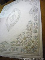 Full view of the large ivory wool rug with floral pattern and central medallion