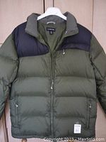 Front view of Land's End men's down jacket, green with navy blue trim on shoulders and collar, zippered front and zippered pockets.