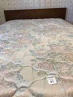 Full view of the walnut headboard and part of the floral quilted mattress cover on the double bed.