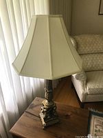 Full view of the lamp showing gold base with cherubs and cream lampshade