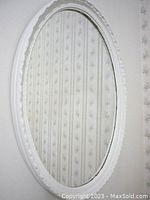 Full view of white oval mirror showing oval shape, white frame, and reflection.
