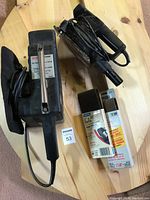 Photo of two power sanders on pine round table top showing Sears Craftsman belt sander with dust bag, Black & Decker sheet sander, and sanding belts.