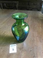 Full view of green and blue art glass vase upright on wooden surface