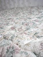 Close view of mattress top surface showing quilted floral pattern fabric in light pastel colors.