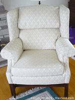 Front view of off-white wingback armchair showing seat cushion and winged back.