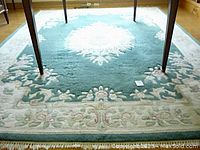 Full view of wool rug under table showing central medallion and border design