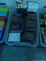 Top view of clear bins containing multiple stacks of mixed Pokémon trading cards, some in plastic protective sleeves, along with card storage boxes and decks.