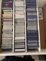 Top view of a large box filled with three sections of assorted trading cards, many sleeved and in graded holders.