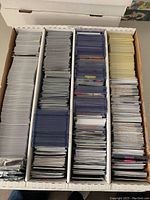 Photo of large collection of mixed sports cards organized in a cardboard box with four compartments