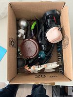 Photo showing a cardboard box filled with assorted Star Wars action figures and toys, including characters, accessories, and parts.