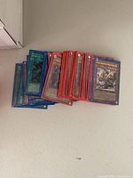 Stack of Yu-Gi-Oh! trading cards showing various monster, spell and trap cards in protective sleeves.