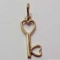 Front-facing photo of the 10K yellow gold pendant shaped like a key with heart designs.