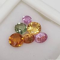 Six loose fancy color sapphires on white background, showing colors and cuts