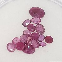 Group of loose rubies in varying shapes and sizes, predominantly oval and round cuts, color shades range from light to darker red, total estimated carat weight around 4ct.