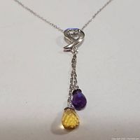 Clear close-up of the necklace pendant showing faceted amethyst and citrine teardrop-shaped gemstones hanging from double silver chain attached to a silver loop with heart detail.
