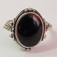 Front view of silver ring displaying large black onyx cabochon stone and surrounding beaded silver detail.
