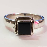 Front view of silver ring with square black onyx stone showing the setting and polished band.