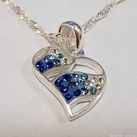 Close-up photo of the silver heart-shaped pendant with blue and clear cubic zirconia stones showing detail of stones and pendant design.