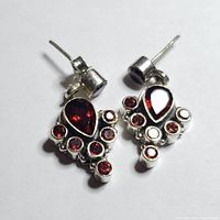 Pair of silver garnet stud earrings shown from above on white background, showing detailed arrangement of garnet stones in a polished silver setting.