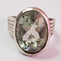 Front view showing oval faceted green amethyst stone set in sterling silver bezel with ridged band.