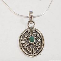 Front view showing detailed silver pendant with green onyx stone on silver chain.