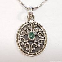 Close-up front view of oval silver pendant with green onyx center on box chain necklace