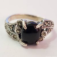 Close-up front view of the silver ring with black onyx center and marcasite detailing on the sides.