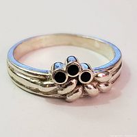 Front view of the silver ring showing four black round stones in a cluster design on band.