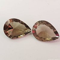Two pear-shaped faceted smokey quartz gemstones shown from top angle against white background.